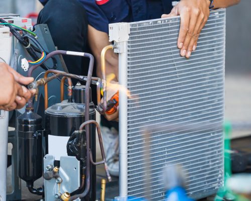 Close up of Air Conditioning Repair team use fuel gases and oxygen to weld or cut metals, Oxy-fuel welding and oxy-fuel cutting processes, repairman on the floor fixing air conditioning system