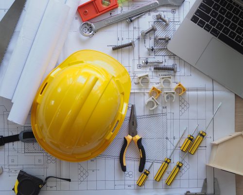 Contractor's desk and engineering team. There are blueprints, hard hats and various accessories.