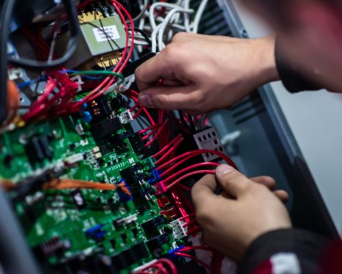 Closeup of electrician engineer working with electric cable wires of modern fuse switch box. Electrical equipment adjusting new voltage wiring